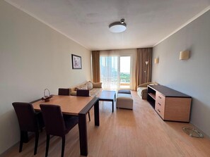 Een moderne woonkamer met een eethoek, een bank, een salontafel en een tv-meubel.