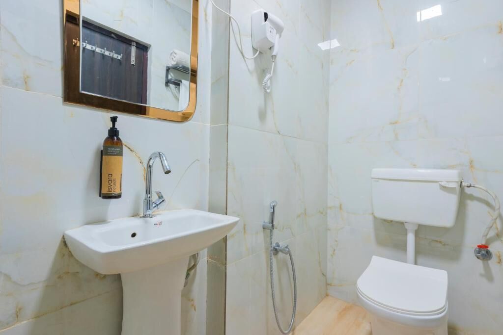 A bathroom with a white sink, a mirror, a handheld showerhead, and a toilet.