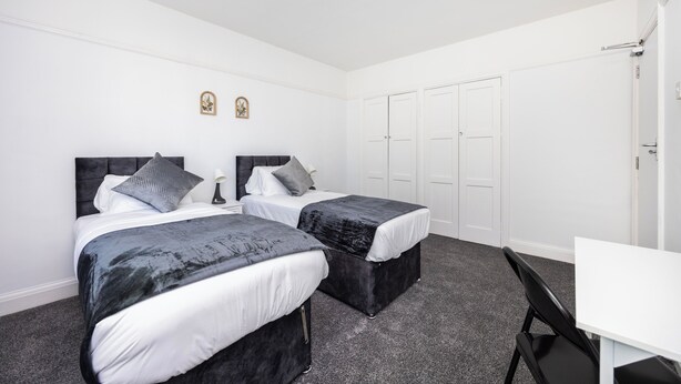 Una habitación de hotel con dos camas, un escritorio y un armario.