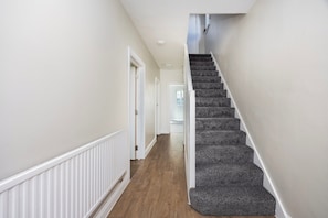 A hallway with a carpeted staircase leading to an upper floor. - 8 Bed - Sleeps 14 - Large Garden - Parking 10 Cars (Tilbury)
