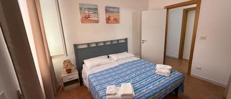 A bedroom with a bed, a nightstand, a lamp, and two paintings on the wall.