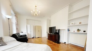 Ein geräumiges Zimmer mit einem großen Bett, einem Fernseher, einem Kleiderschrank und einer Heizung.