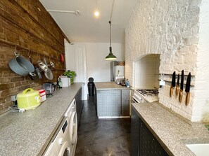 A kitchen with a washing machine, a coffee maker, and hanging pots. - Stylish Retreat at Hyde Park Mansions (London)