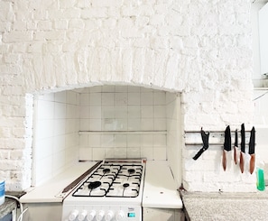A kitchen with a white gas stove, a tiled backsplash, and hanging knives. - Stylish Retreat at Hyde Park Mansions (London)