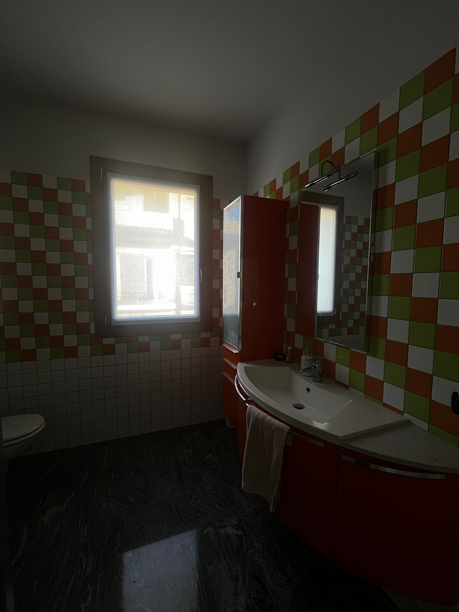 Une salle de bain avec une fenêtre, un lavabo et un miroir.