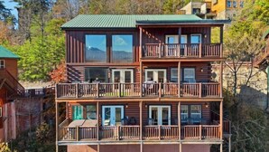 A multi-story log cabin with balconies, large windows, and a green roof. - Robin's View | Hot Tub, Indoor Pool, Unbeatable Mountain Views! (Pigeon Forge)