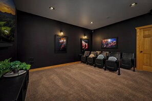 A home theater room with a dark wall, a wooden door, and a carpeted floor. - Robin's View | Hot Tub, Indoor Pool, Unbeatable Mountain Views! (Pigeon Forge)