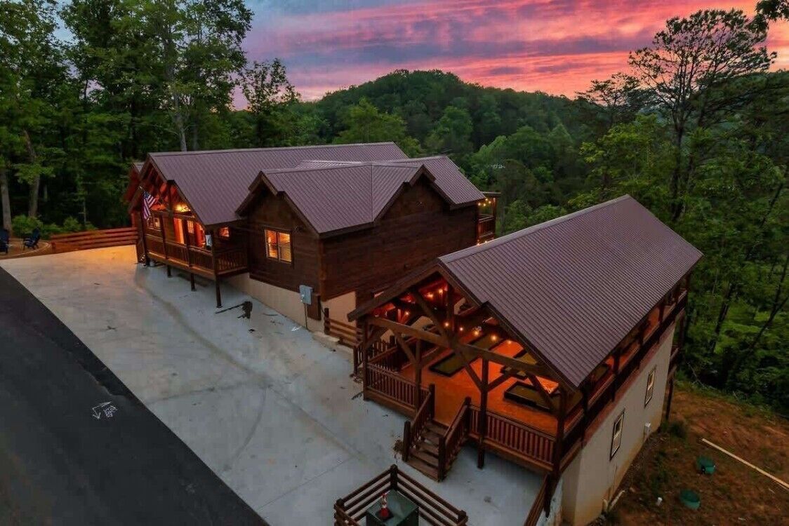 Une cabane dotée d’un porche et d’un espace extérieur aménagé et abrité, entourée de forêt.