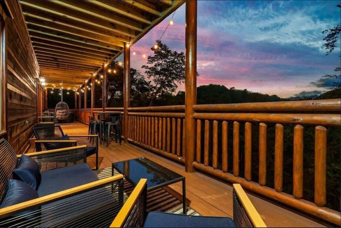 A wooden deck with outdoor seating and a railing overlooking a natural landscape.