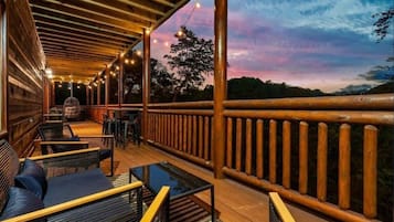 A wooden deck with outdoor seating and a railing overlooking a natural landscape.