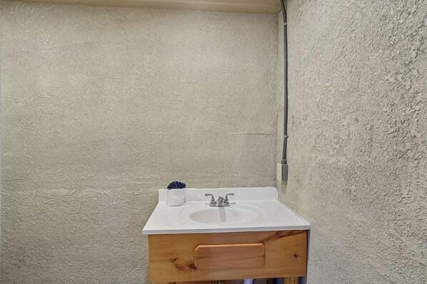 A bathroom with a white sink, wooden cabinet, and a towel rack.
