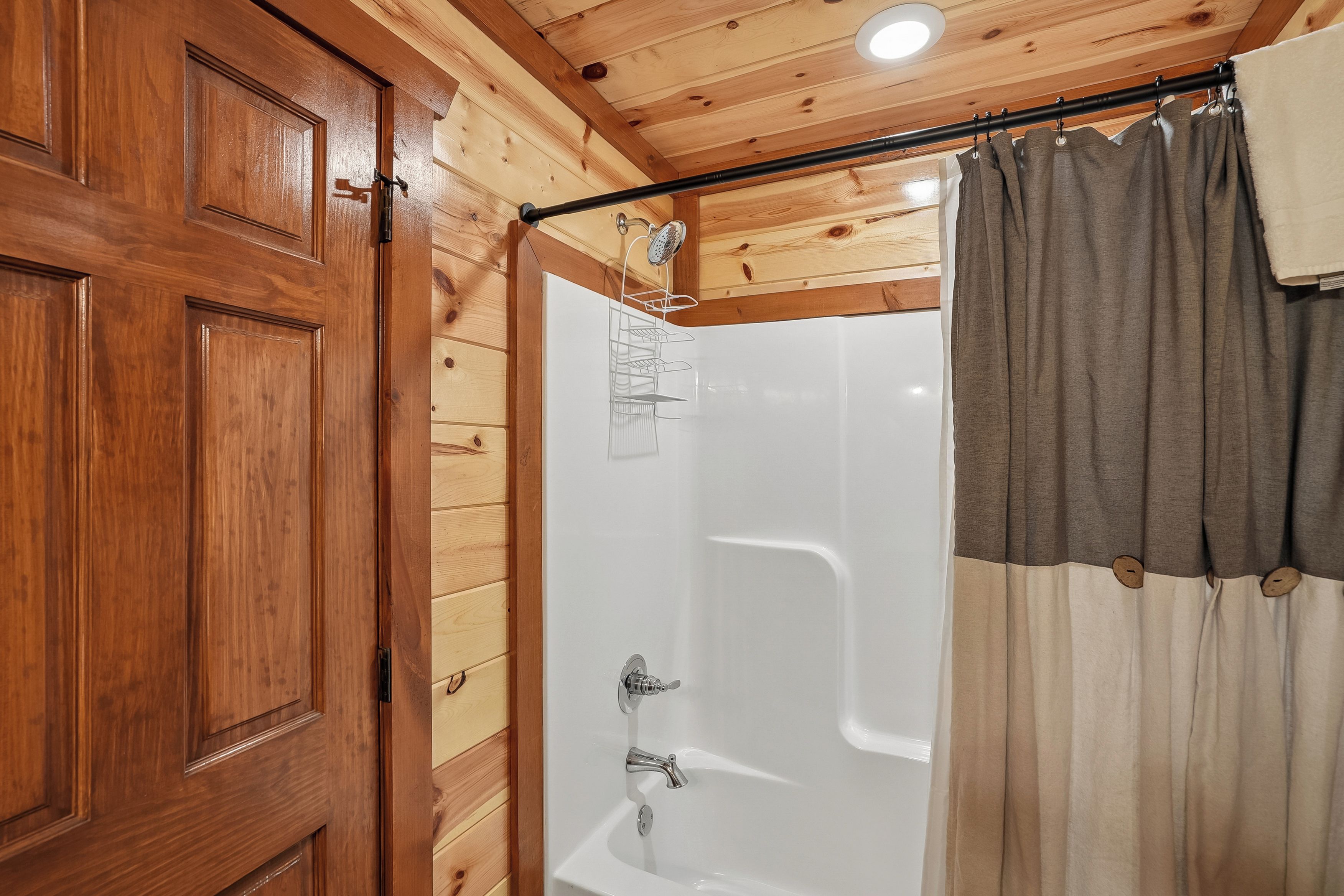 A wooden-paneled bathroom with a white bathtub, a shower, and a curtain.