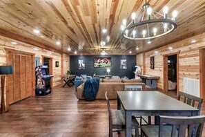 A log cabin interior with a dining area, sofa, and entertainment unit.