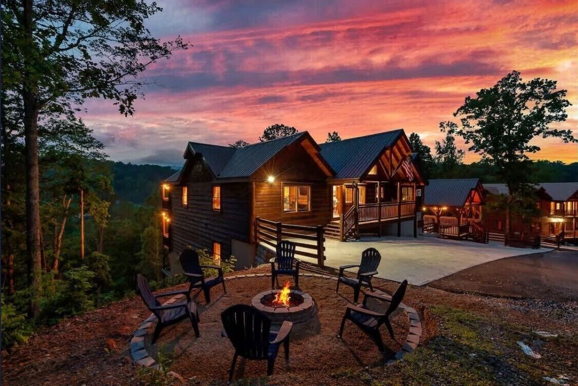 A lodge with a fire pit and outdoor seating, surrounded by a wooden deck and a scenic view.