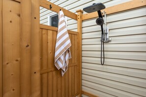 Een houten deur met een handdoek aan een haak, een douchekop aan de muur, en een raam boven de deur.