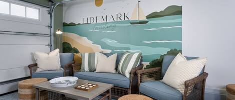 A room with a sofa set, wicker chairs, a coffee table, and a mural with the text 'LIDEMARK'.