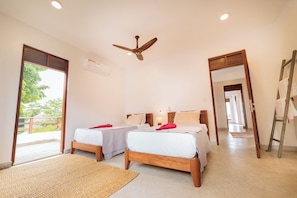 A hotel room with two beds, a ceiling fan, and a view of the outdoors.