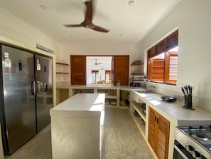 A modern kitchen with a central island, stainless steel appliances, and a ceiling fan.