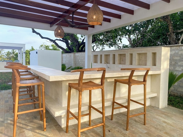 An outdoor bar area with wooden stools and a stone countertop.