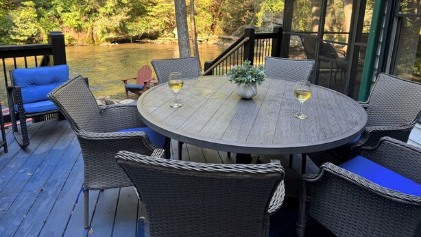 Eine Terrasse mit Korbmöbeln, zwei Weingläsern und einem Blumentopf.