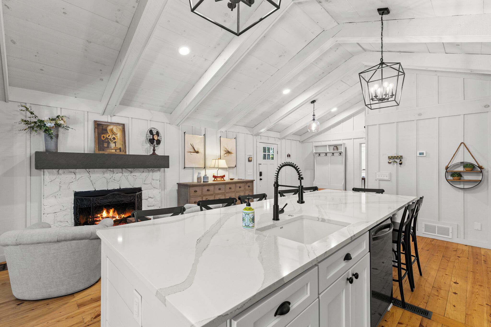 A modern kitchen with a central island, white cabinetry, and a fireplace.