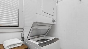 Eine kompakte, weiße Waschmaschine und Trockner-Kombination mit Holzablage und einem weißen Handtuch.