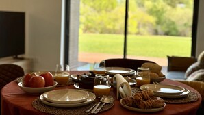 A breakfast table set with plates, cutlery, and a bowl of apples. - Vilamoura Prestige 3 With Pool by Homing (Loulé)