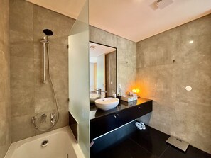 Une salle de bain moderne équipée d’une baignoire, d’une douche à parois de verre, d’un meuble-lavabo et d’un miroir.