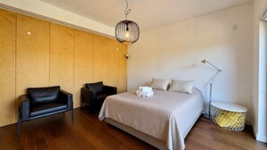 A modern bedroom with a large bed, two black chairs, a floor lamp, and a unique hanging light fixture. - Vilamoura Prestige 3 With Pool by Homing (Loulé)