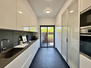 A narrow kitchen with a countertop, a sink, and a stove. There is a sliding glass door leading to an outdoor area. - VILAMOURA PRESTIGE 3 WITH POOL by HOMING (Vilamoura)