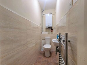 Ein schmales Badezimmer mit Toilette, Bidet und einem Händetrockner.