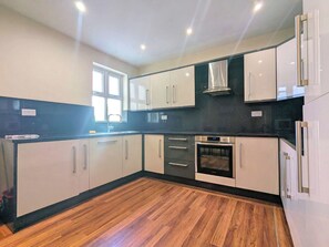 Eine moderne Küche mit weißen Schränken, einer schwarzen Arbeitsplatte und einem eingebauten Backofen.