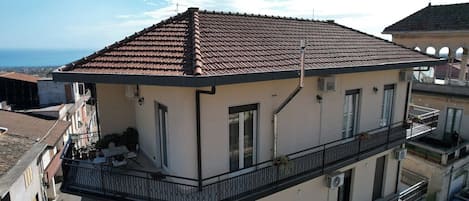 Un edificio de varios pisos con techo de tejas, balcones con barandillas y un equipo de aire acondicionado.