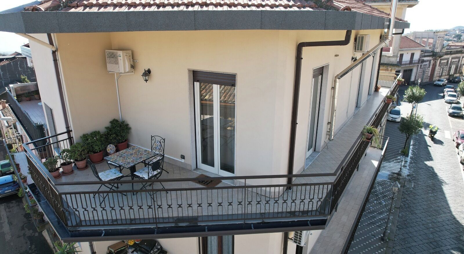 Ein Wohngebäude mit Balkon, Blumentöpfen und einem Tisch mit Stühlen.