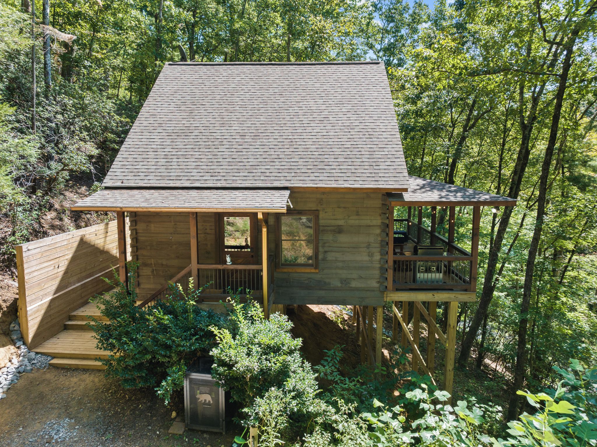 A wooden cabin with a porch, a staircase, and a deck.