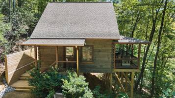 A wooden cabin with a porch, a staircase, and a deck.