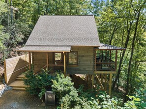 Une cabane en bois avec une véranda, un escalier et une terrasse.