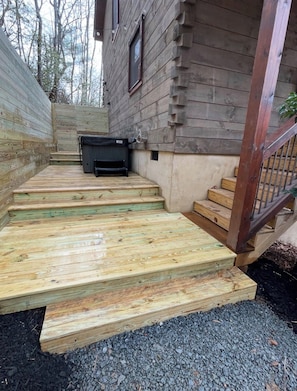 A wooden staircase leading to a deck area with a hot tub.