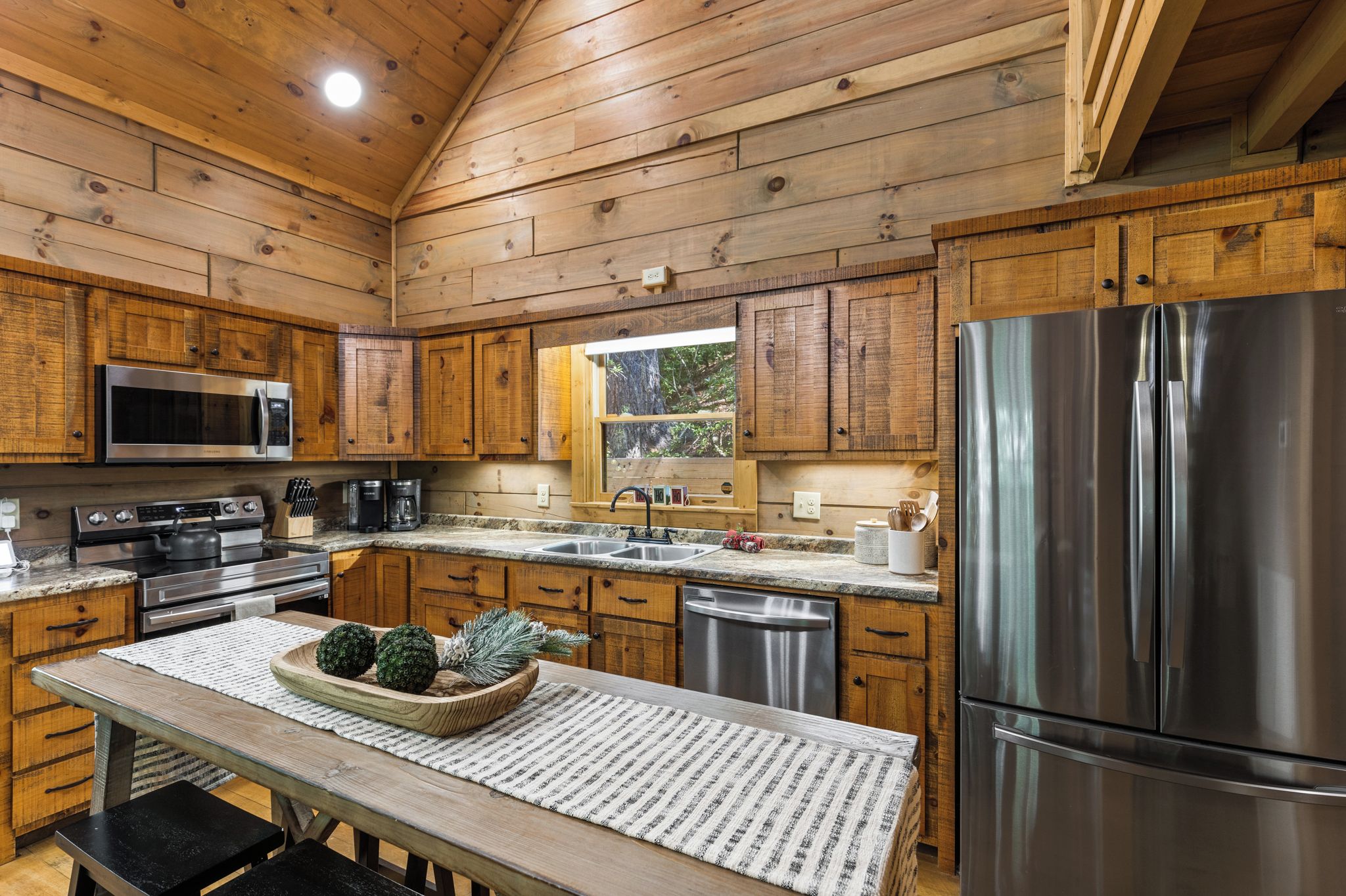 Una cocina moderna con armarios de madera, electrodomésticos de acero inoxidable y un ventanal grande.