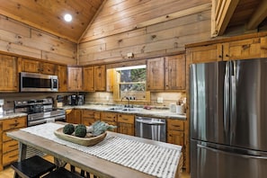 Une cuisine moderne avec des meubles en bois, des appareils électroménagers en acier inoxydable et une grande fenêtre.
