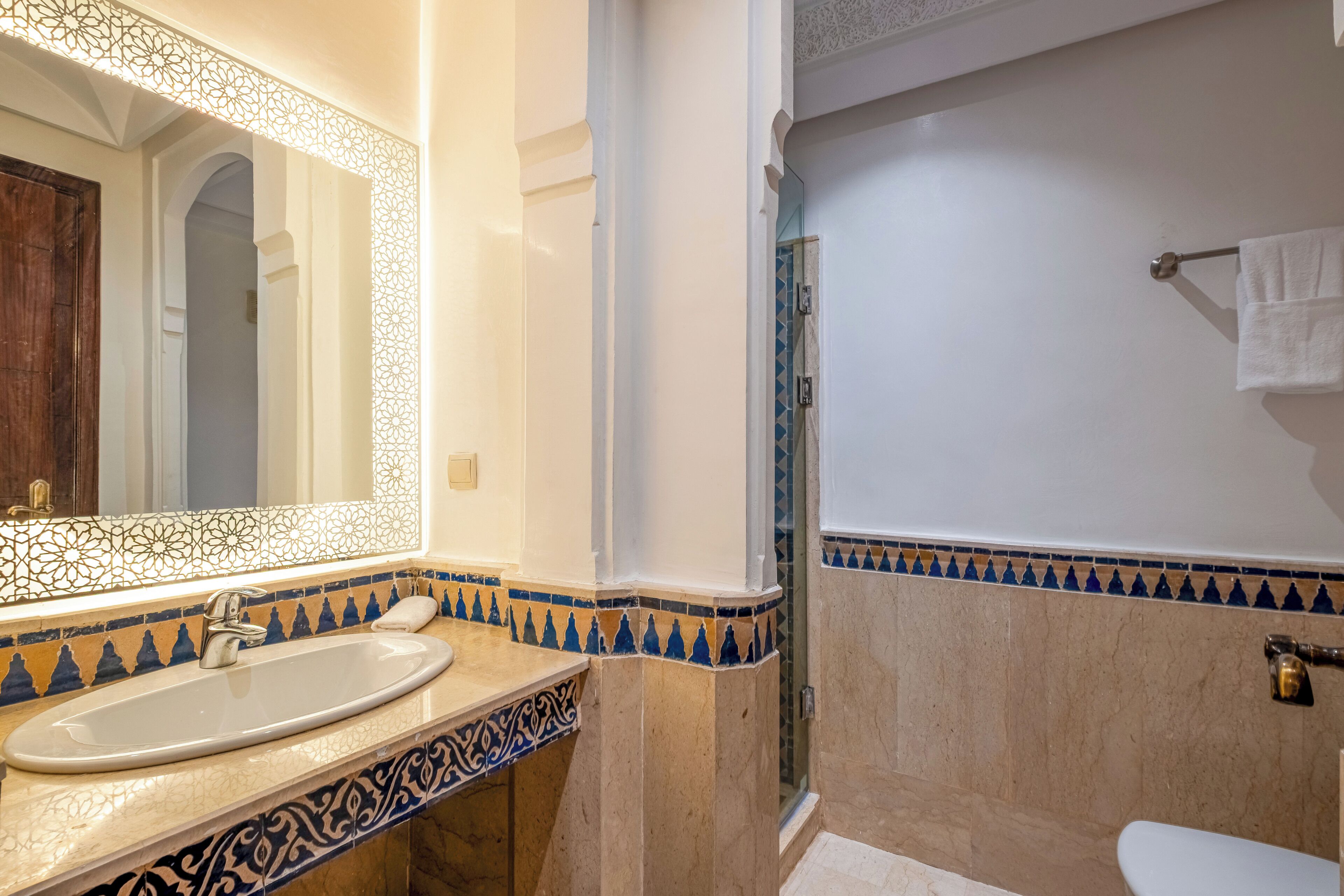 A bathroom with a sink, mirror, and shower area.