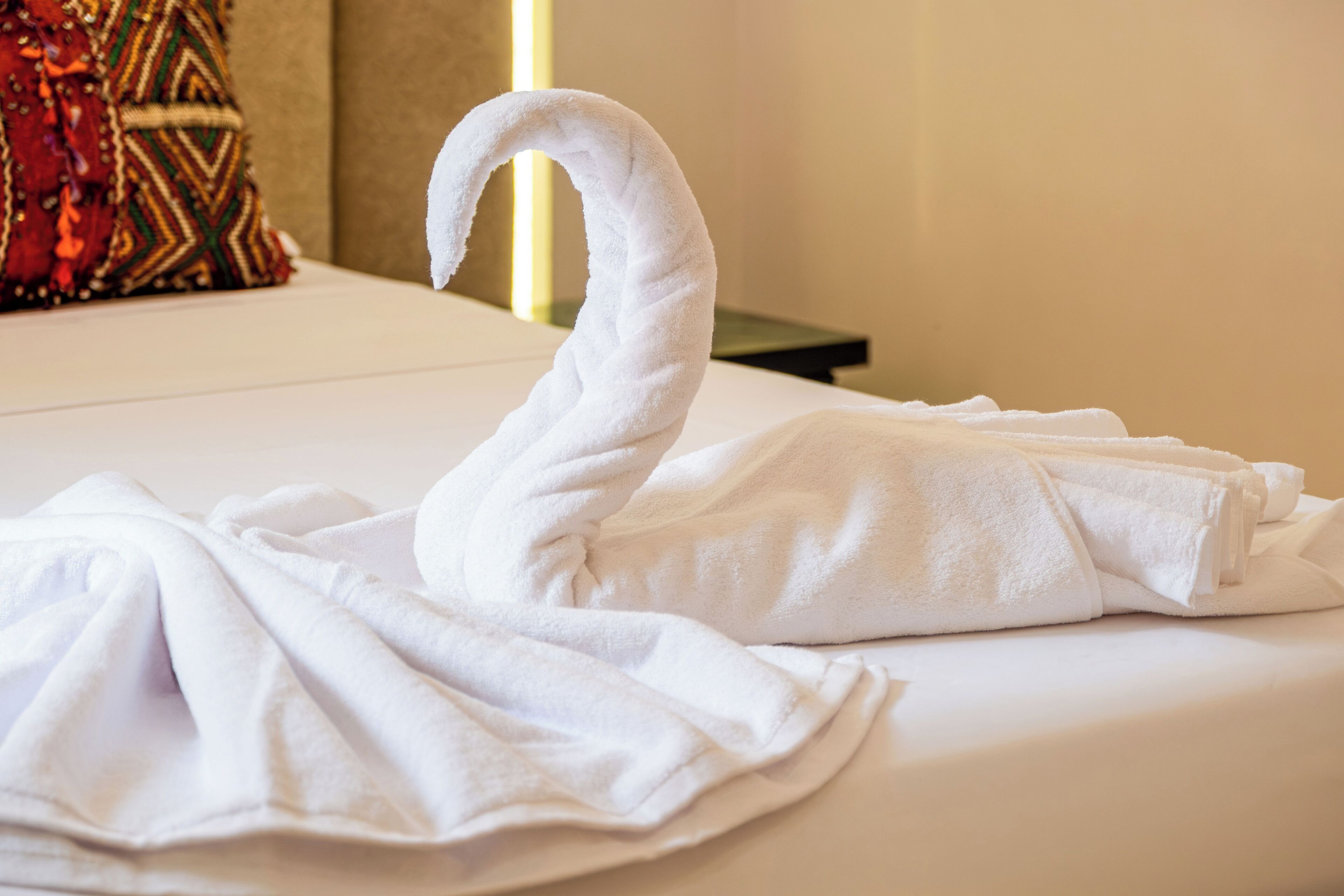 Ein Bett mit einem Handtuch, das zu einem Schwan geformt ist.