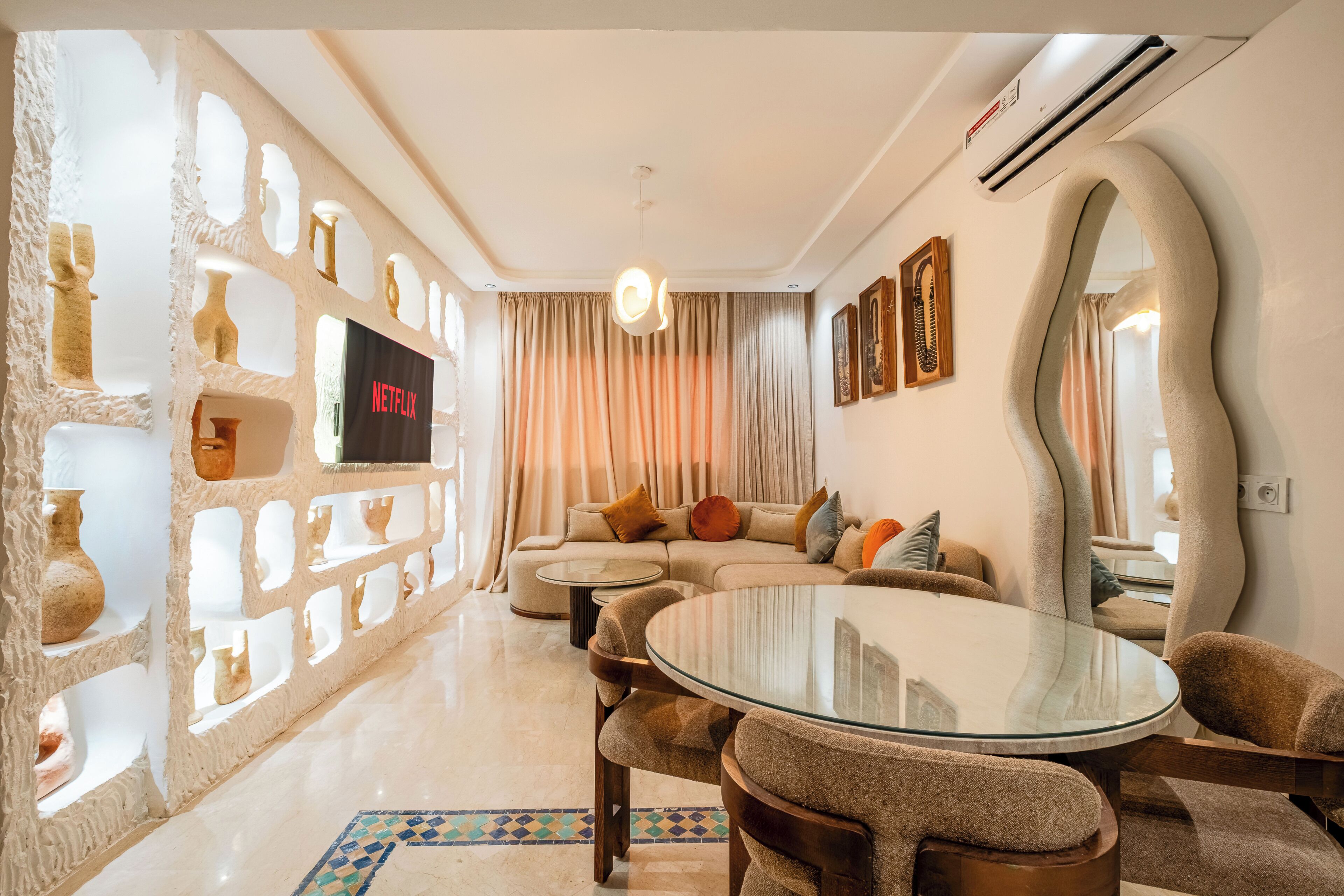 A modern living room with a sectional sofa, a glass coffee table, and a large mirror.