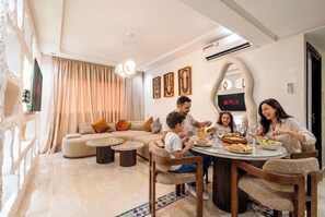 Ein modernes Wohnzimmer mit Essbereich, einer Sofagarnitur, einem Couchtisch und einem an der Wand befestigten Fernseher.