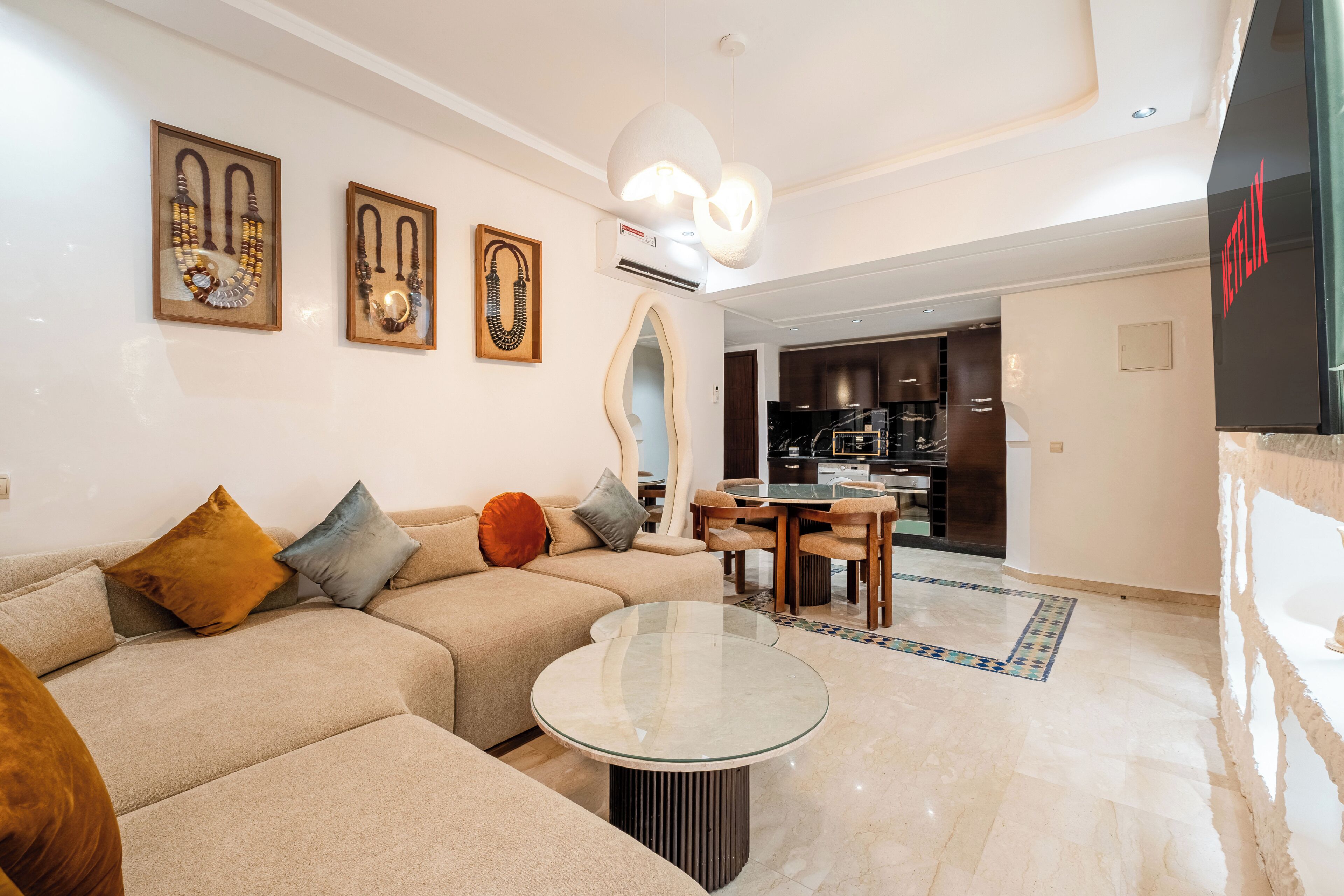Uma sala de estar moderna com um sofá, uma mesa de centro de vidro e uma área de refeições com cadeiras.