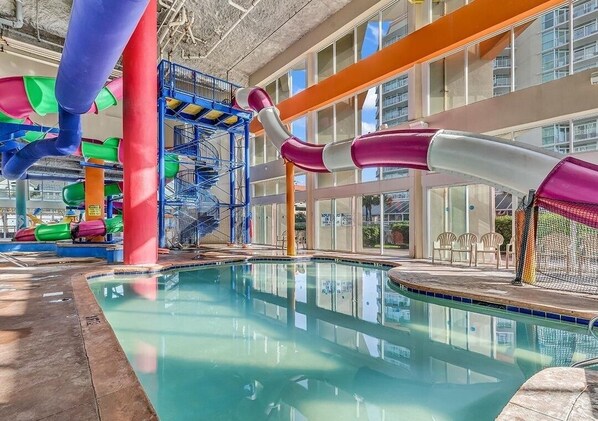 Un área de piscina interior con un tobogán de agua y una piscina.