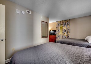 A hotel room with two beds, a mirror, a television, and a wardrobe. - Dunes Village 2BR,  Indoor Waterpark + Ocean View (Myrtle Beach)