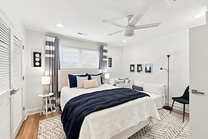 A modern bedroom with a bed, bedside tables, a ceiling fan, and a window with curtains. - Modern Oceanfront Beach Club Villa *Unit 4* in Wild Dunes w/Community Pool! Screen Porch!! (Isle Of Palms)