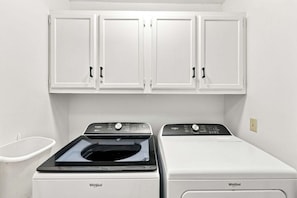 A laundry room with two Whirlpool washers and dryers, white cabinets above, and a white basin to the left. - Modern Oceanfront Beach Club Villa *Unit 4* in Wild Dunes w/Community Pool! Screen Porch!! (Isle Of Palms)