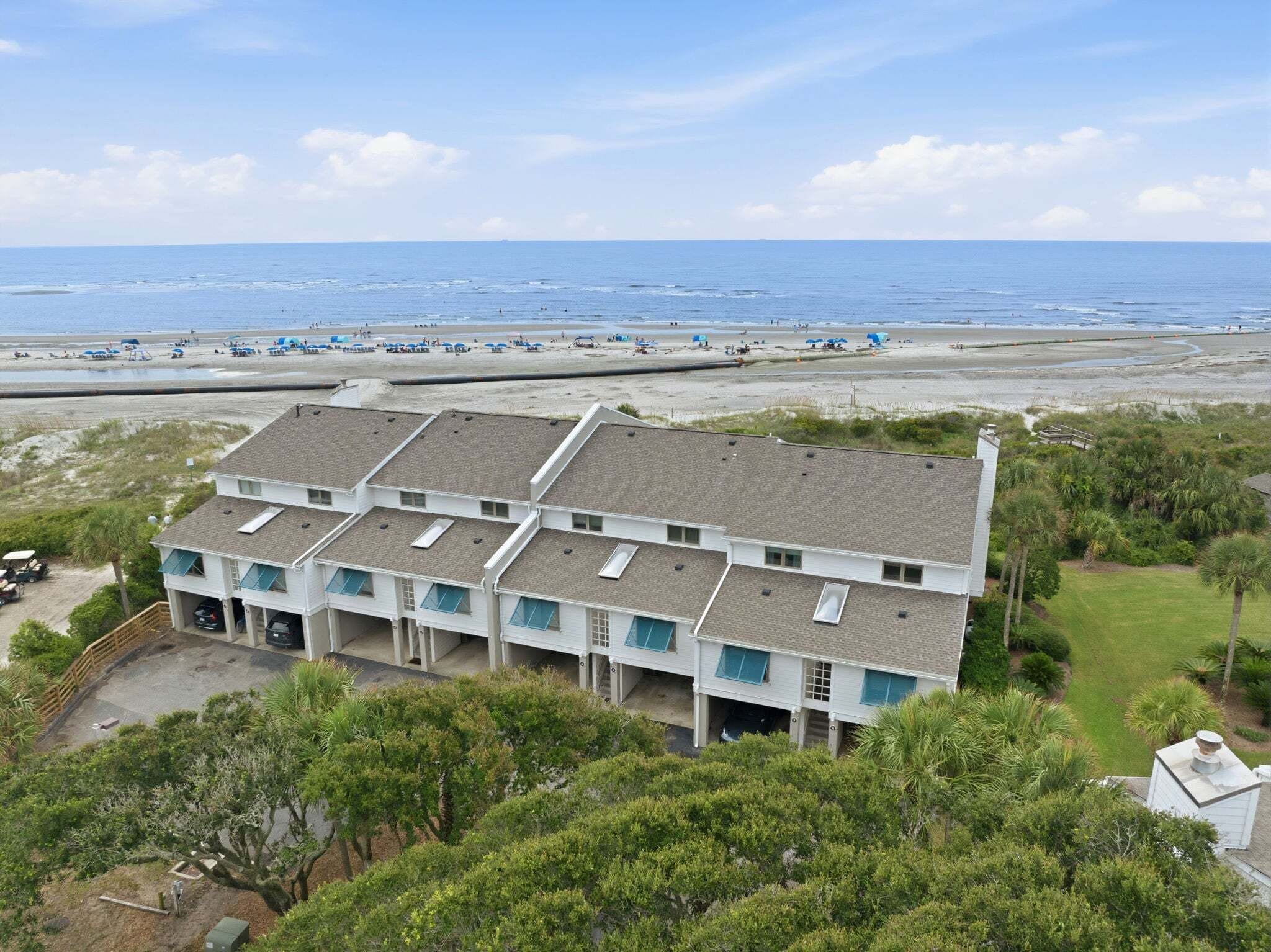 A multi-story building with a flat roof, located near a beach with visible sand and water.